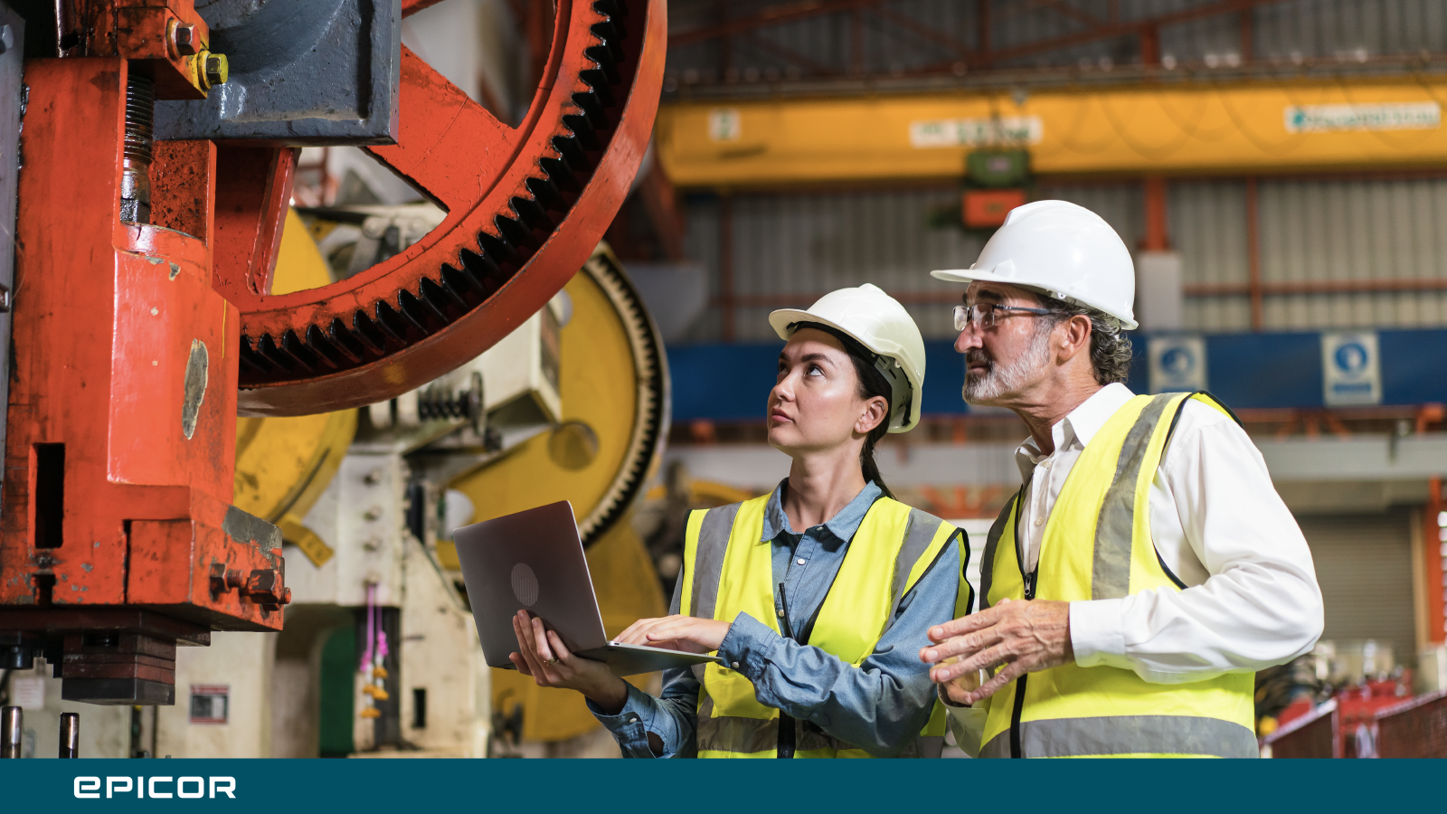 operators viewing factory machinery while working on laptop